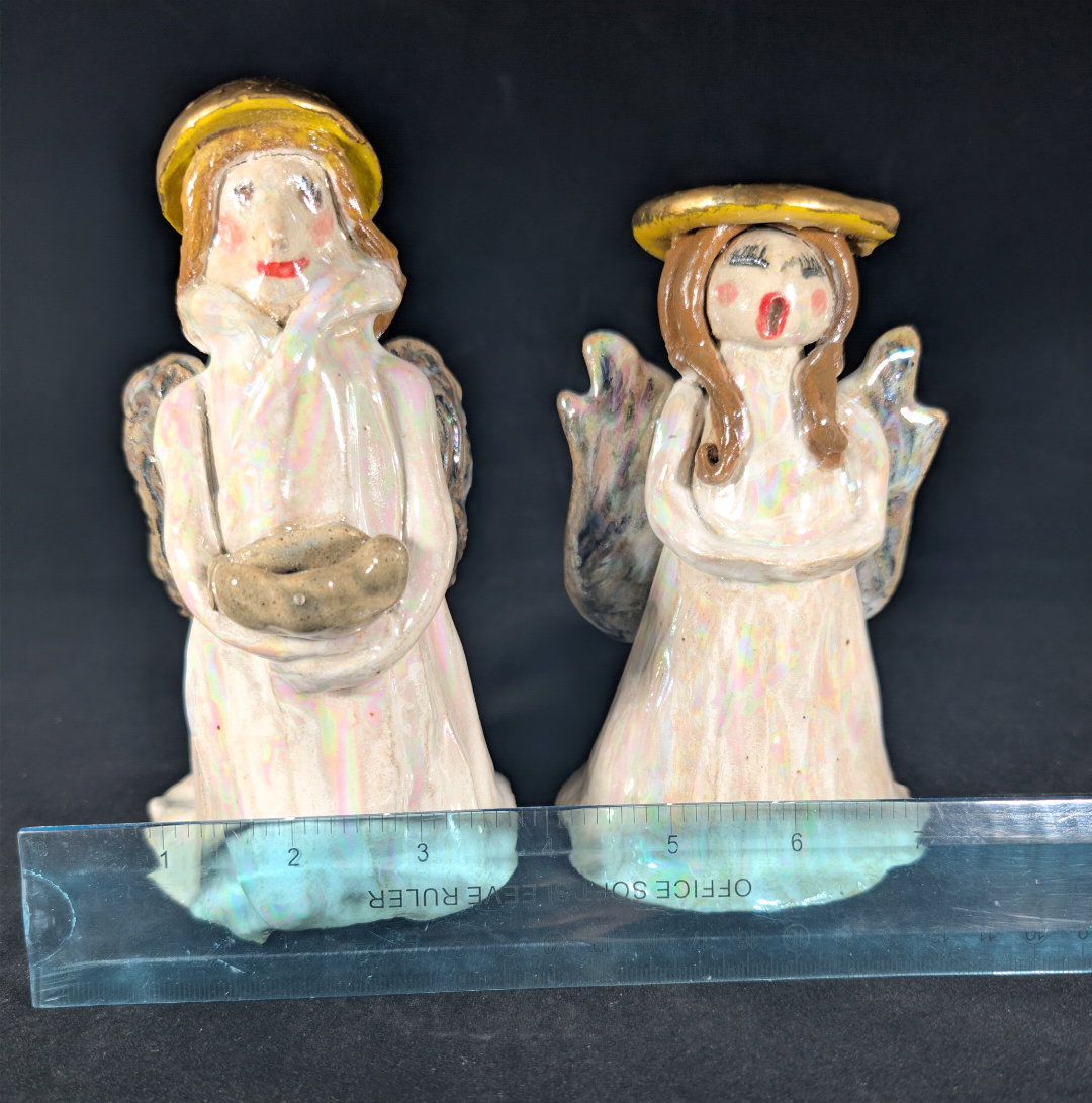 Two angel figurines on a black background