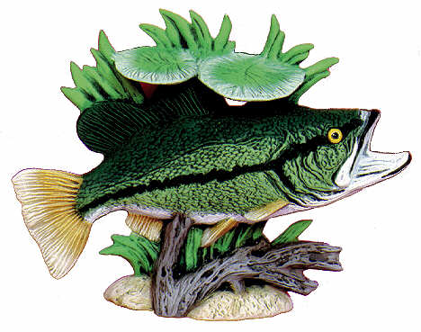 A decorative fish sculpture or wall decor piece featuring a green bass-like fish with a yellow eye, yellow-tinted fins, and a dark horizontal stripe, mounted above driftwood and green aquatic plants on a white background.