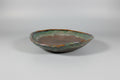 Ceramic dish with green and brown glaze on a black surface