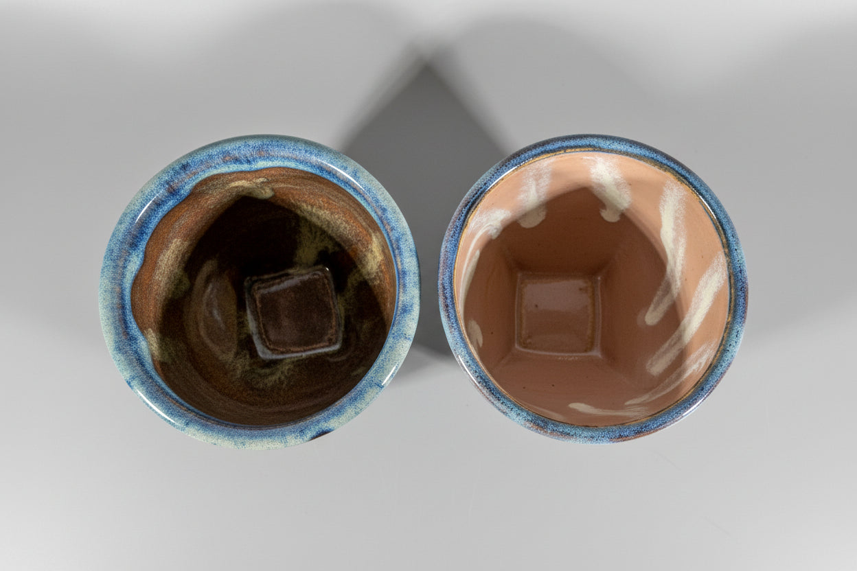 Two ceramic containers with marbled interior designs on a dark background