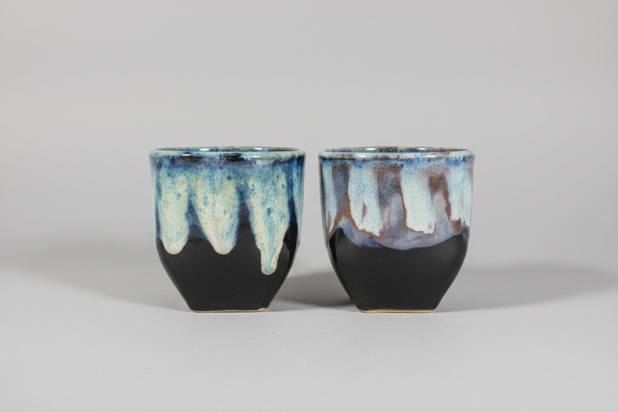 Two ceramic cups with a unique glaze pattern on a dark background