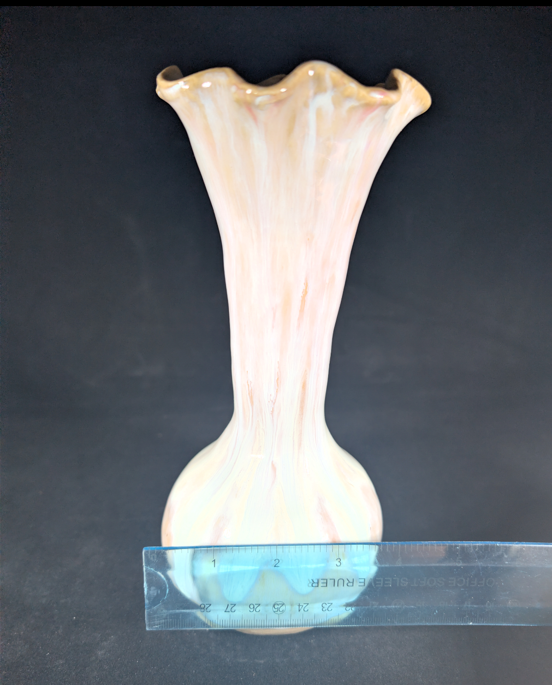 Glass vase with a textured surface and a ruler for scale on a dark background