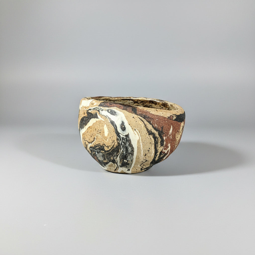 Small ceramic bowl with a matte surface on marbled clay