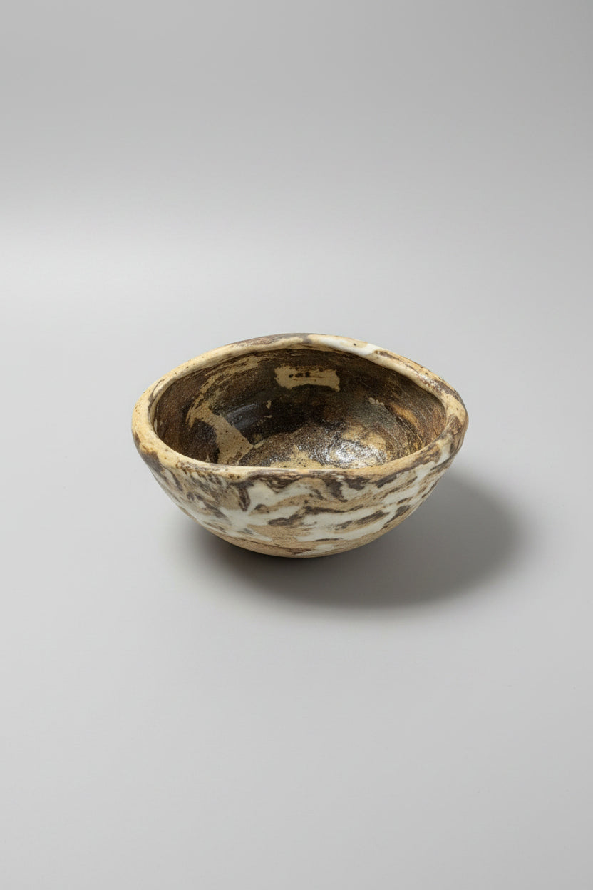 Small ceramic bowl with a matte surface on marbled clay