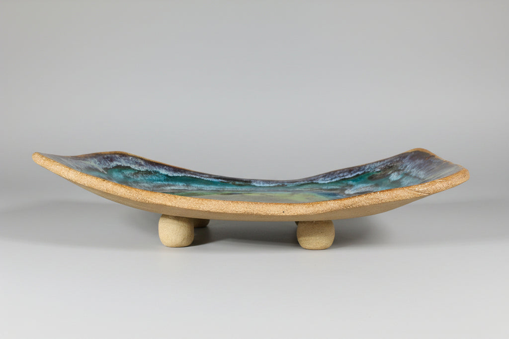 Ceramic dish with a raw edge base on a brown clay