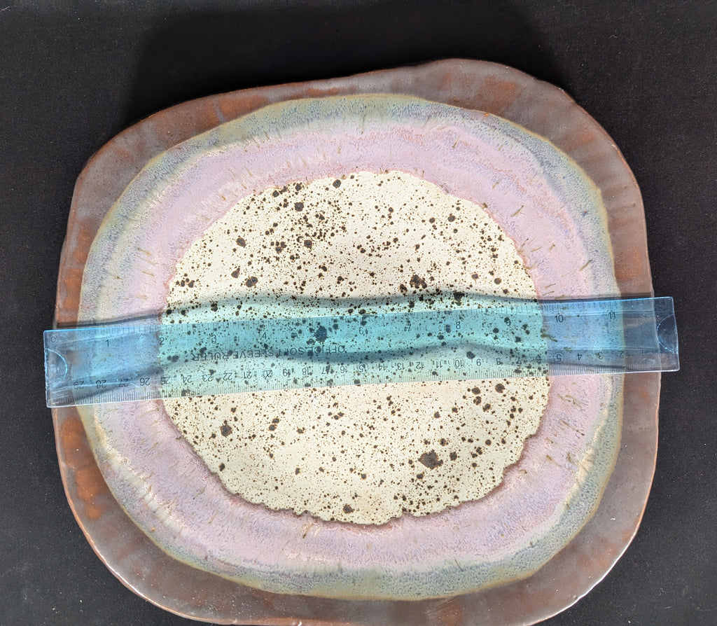 Ceramic plate with a textured center and decorative band on a dark background