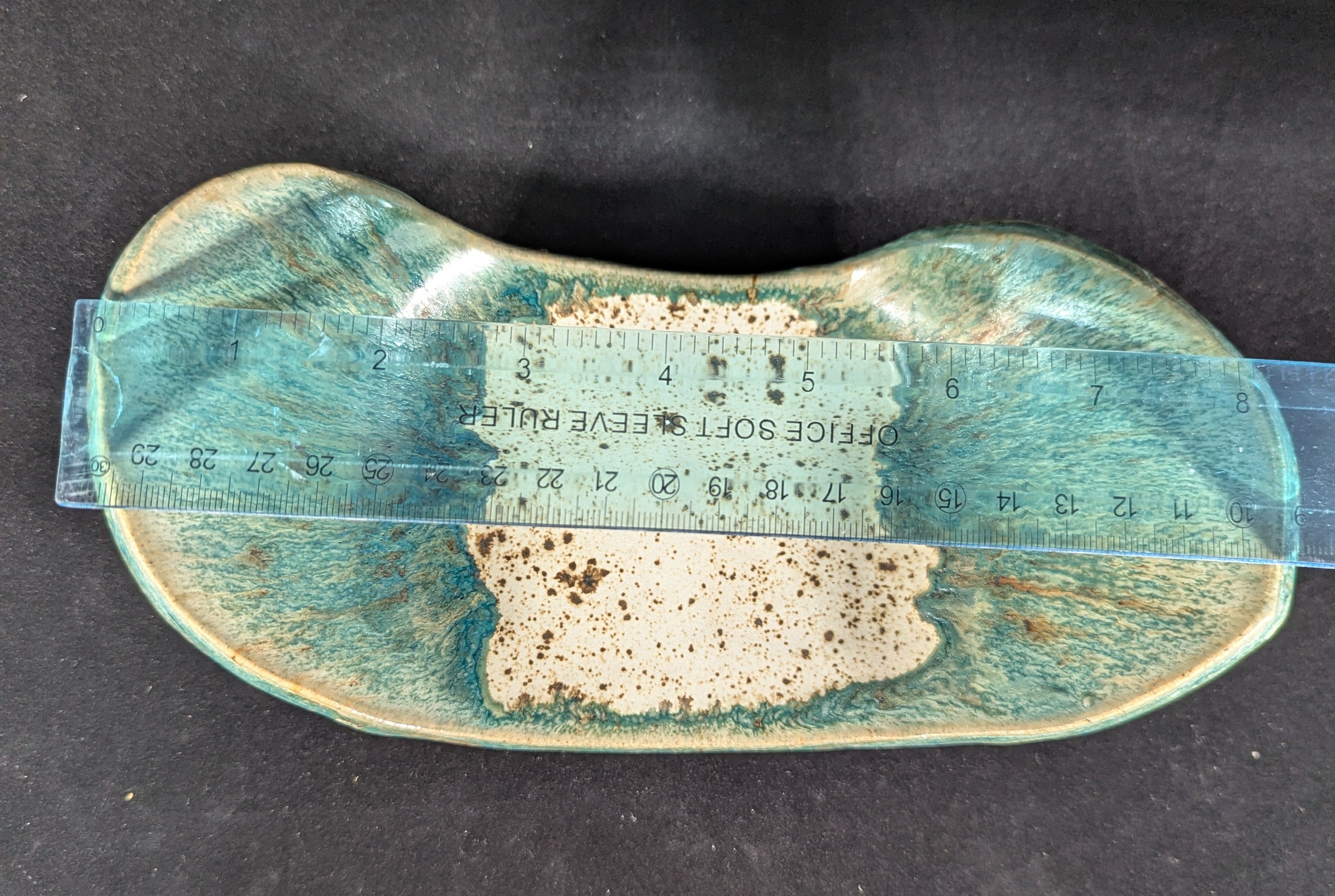 Ceramic dish with textured surface and blue-green glaze on a black background
