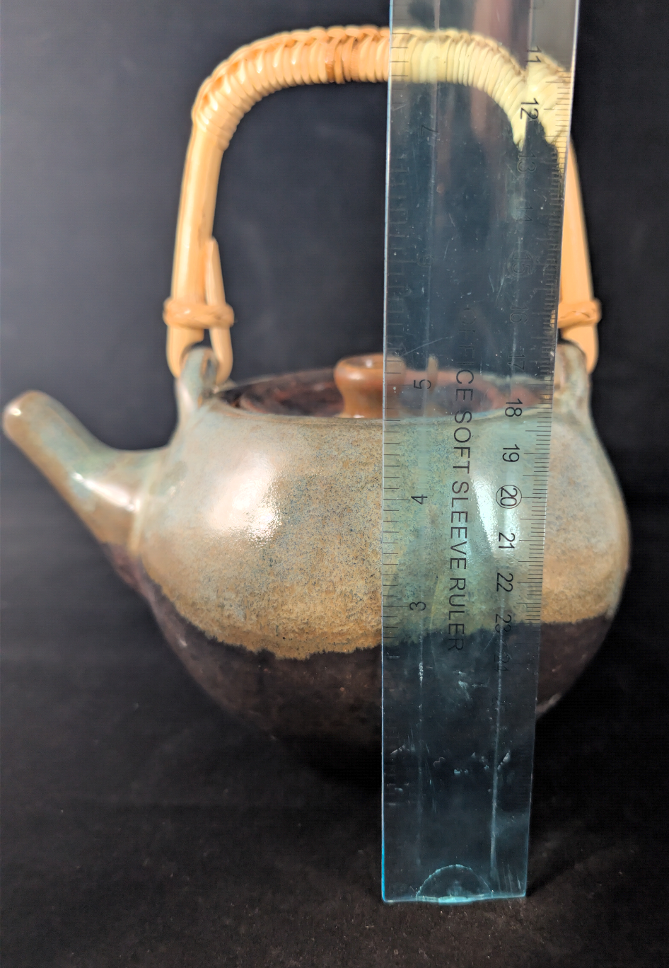 Teapot with a handle and a ruler for scale on a dark background